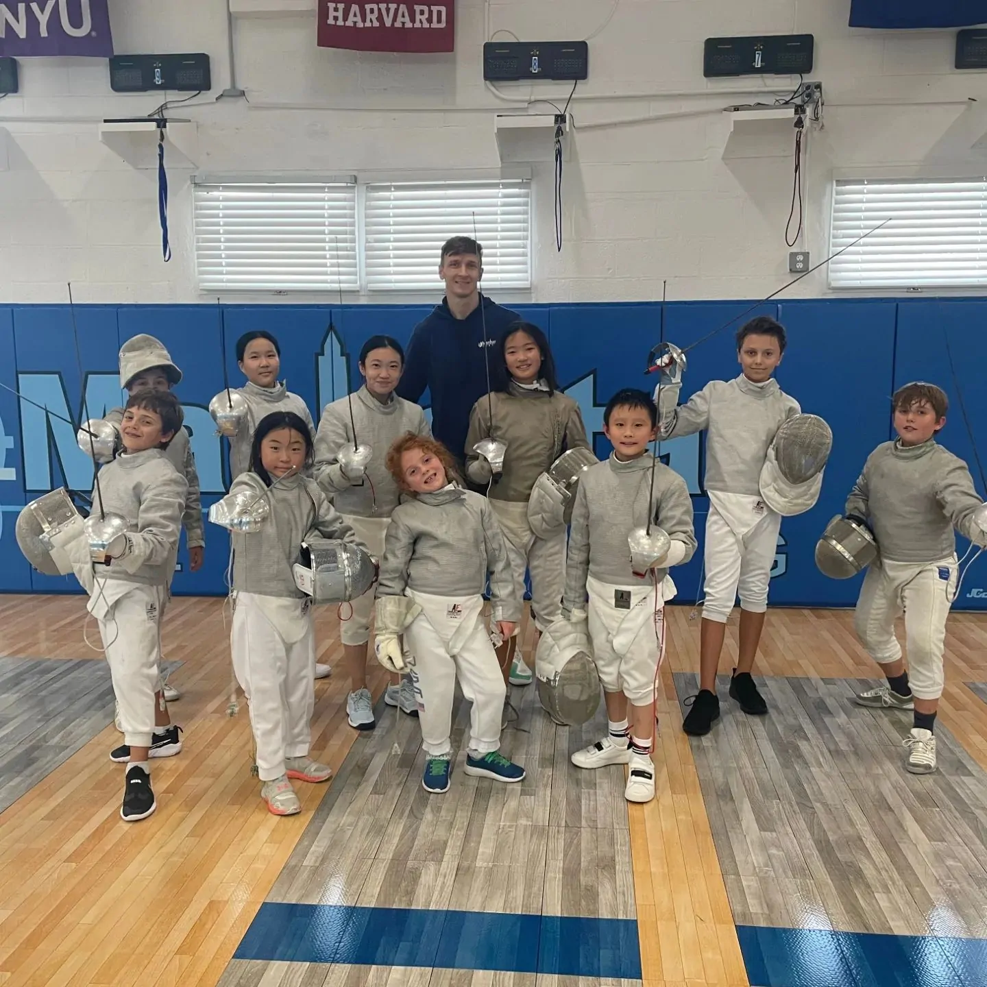 Young fencers in whites on the strips at MFC Englewood